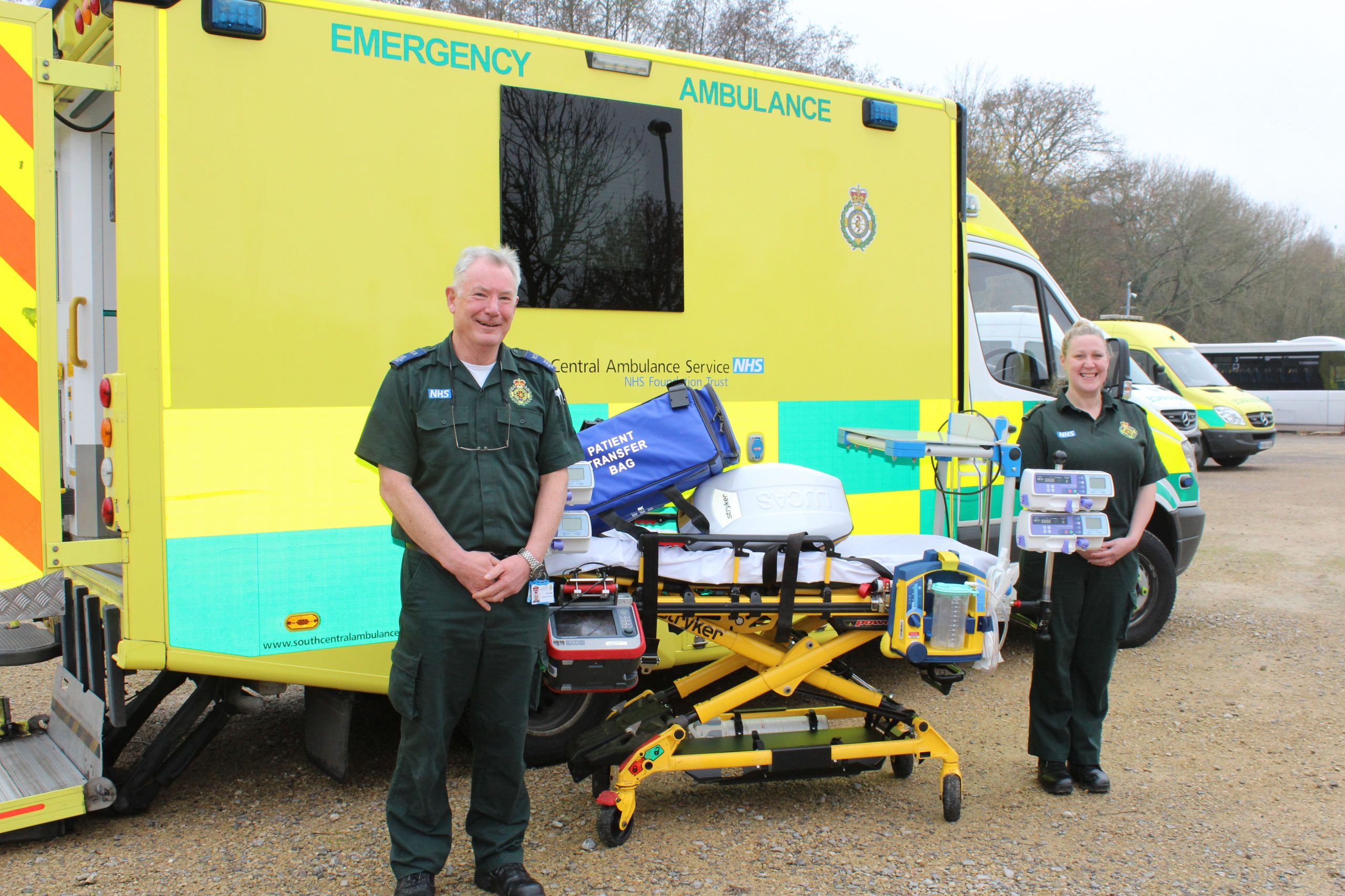 Am ambulance crew and critical care transfer bed standing in front of an ambulance