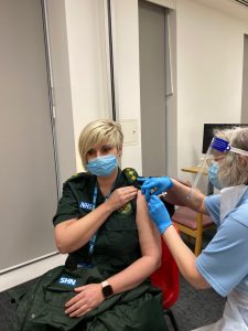 Person seated having vaccine being given by a nurse