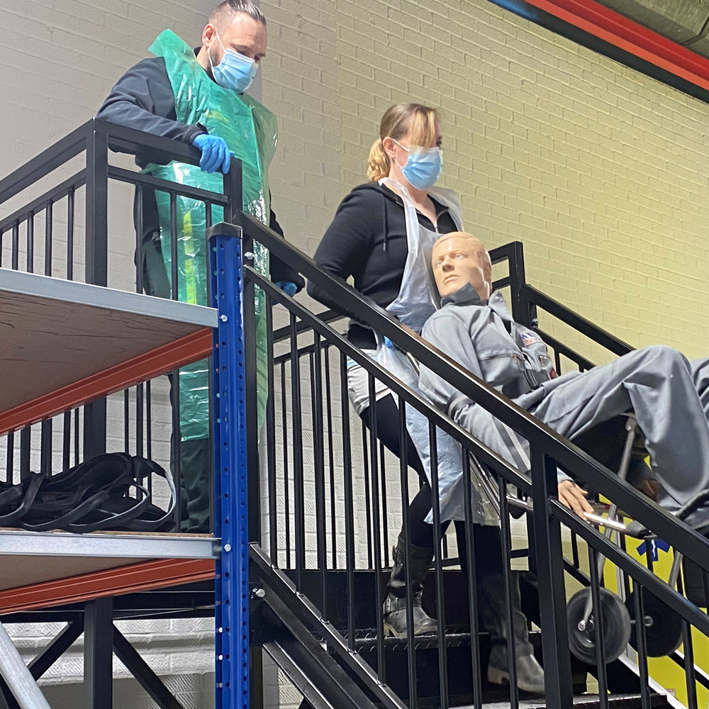 SCAS staff carrying a wheelchair up the stairs