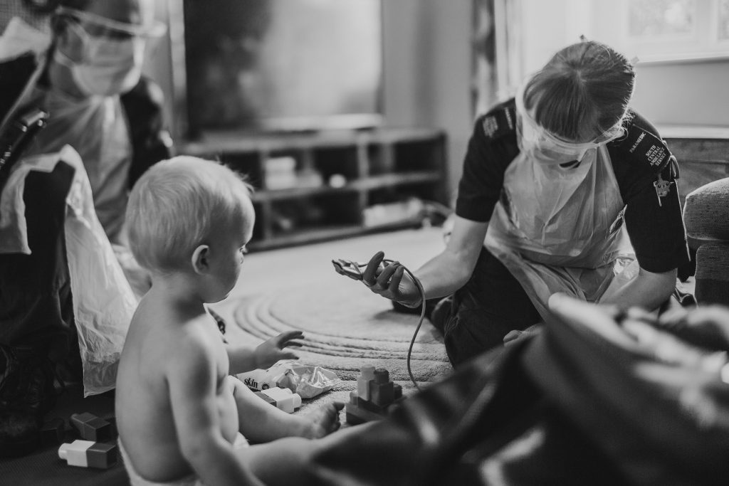 Paramedic playing with baby using saturation monitor