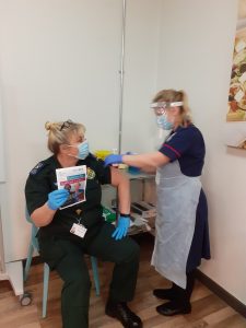 Person seated having vaccine from nurse standing