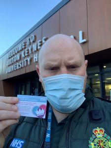 Person holding vaccination card in front of hospital entrance