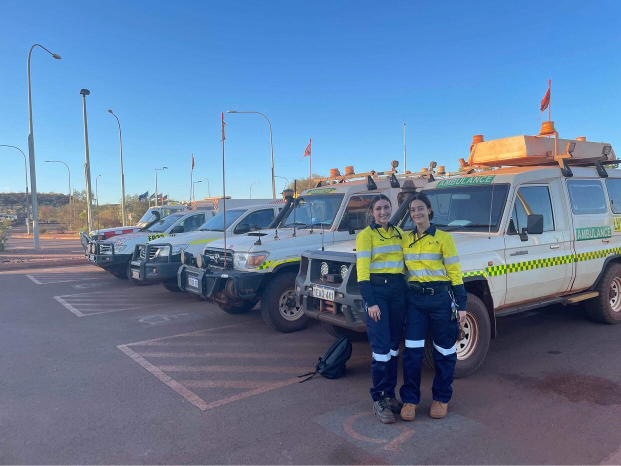 Two Australian newly qualified paramedics standing in front of 4x4 vehicles