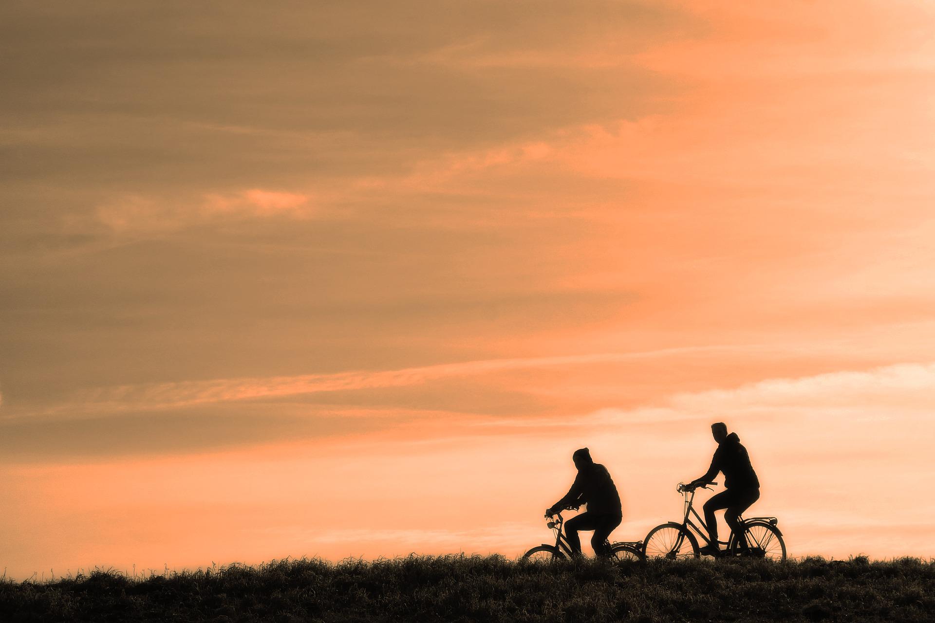 Two people cycling in the sunset