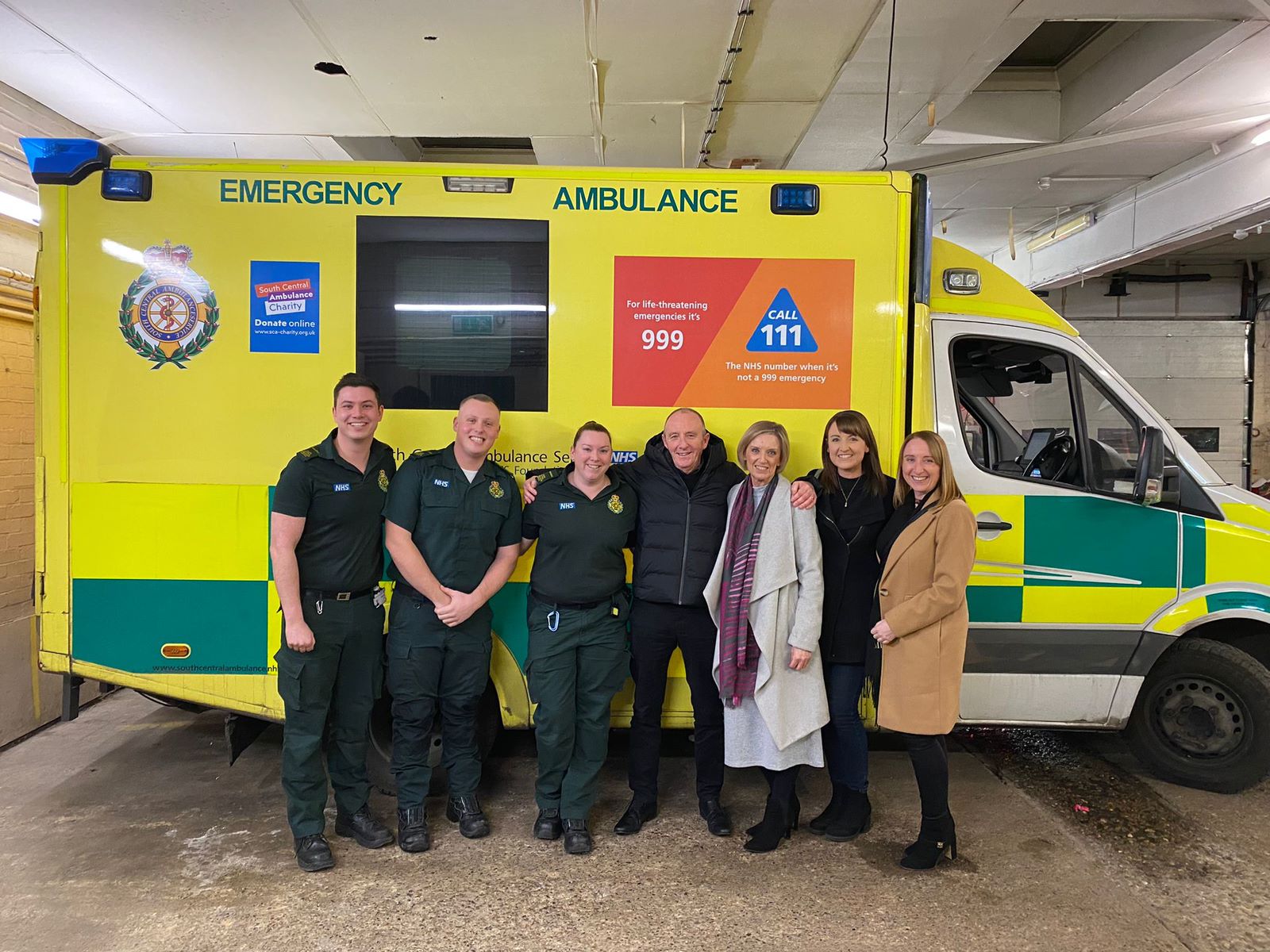 Group of seven people standing in front of an ambulance