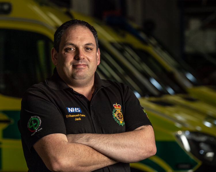 Paramedic standing in front of line of ambulances