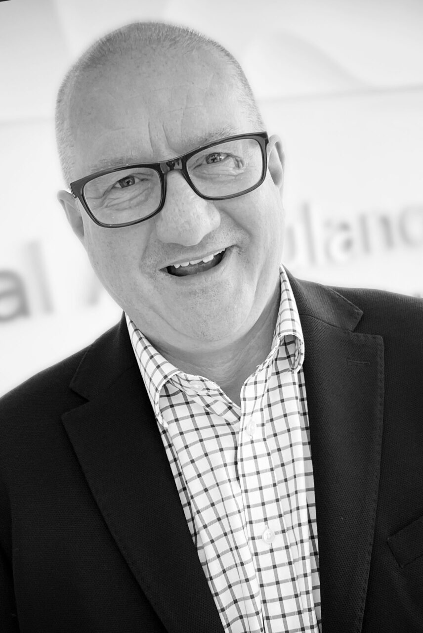 Black and white photo of David Eltringham in front of South Central Ambulance Signage