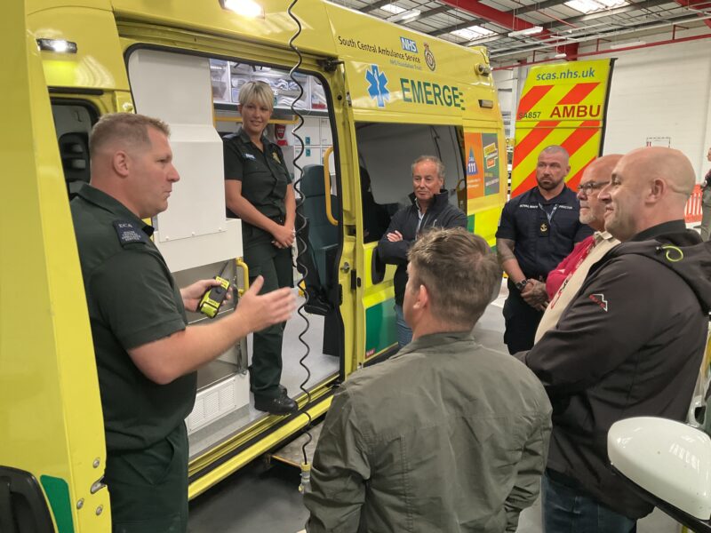 A group of people standing next to an ambulance inside a garage