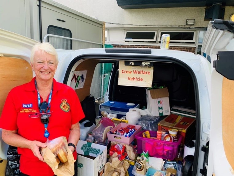 Welfare volunteer next to a van of donated items