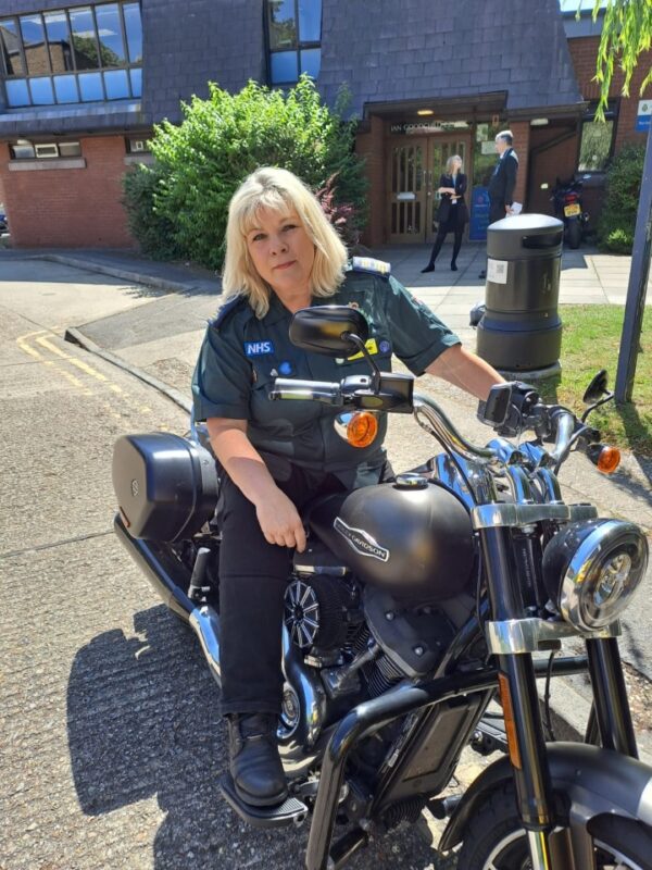 A lady in ambulance uniform sitting on a Harley Davidson motorbike