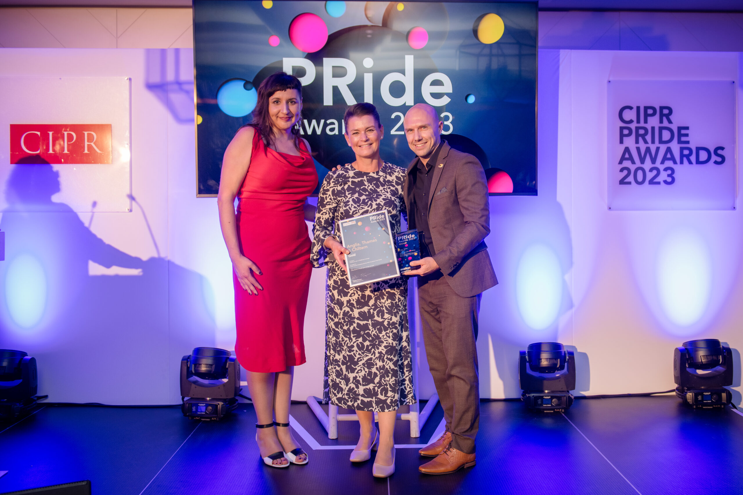 Three people standing on stage at an awards event