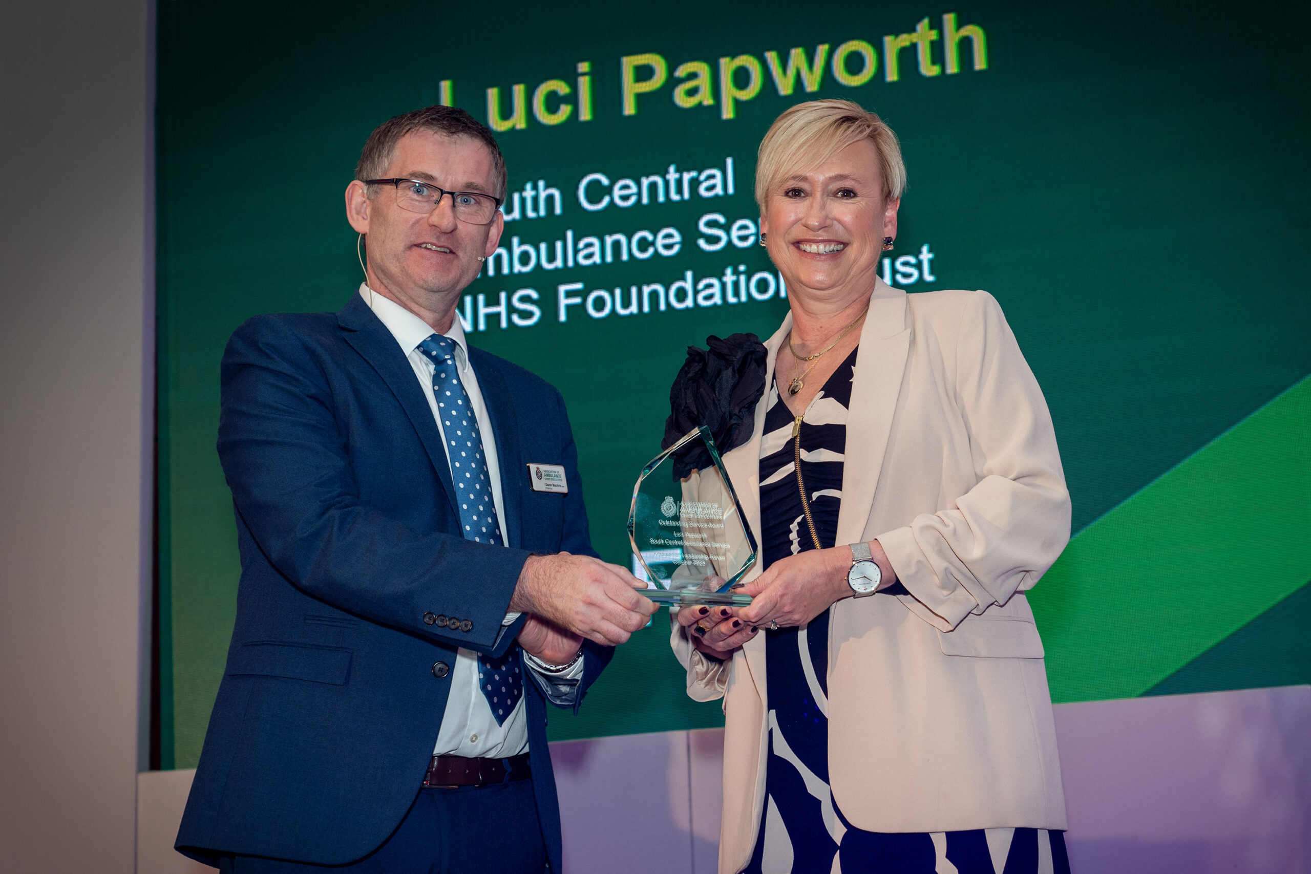 A man shaking hands with a woman who is holding an award