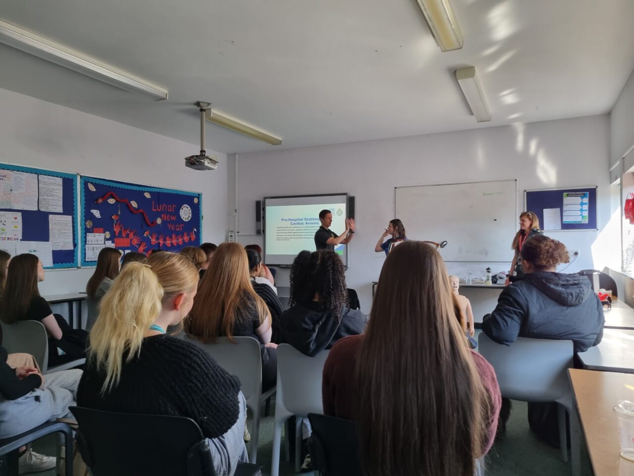 Two paramedics give a first aid training session to a group of seated college students