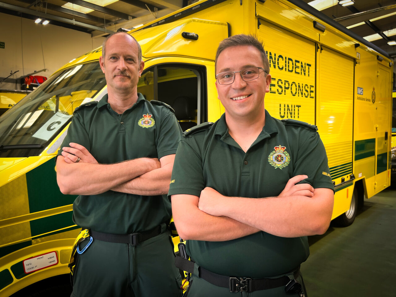 Two HART paramedics standing with arms folded in front of an incident response unit vehicle