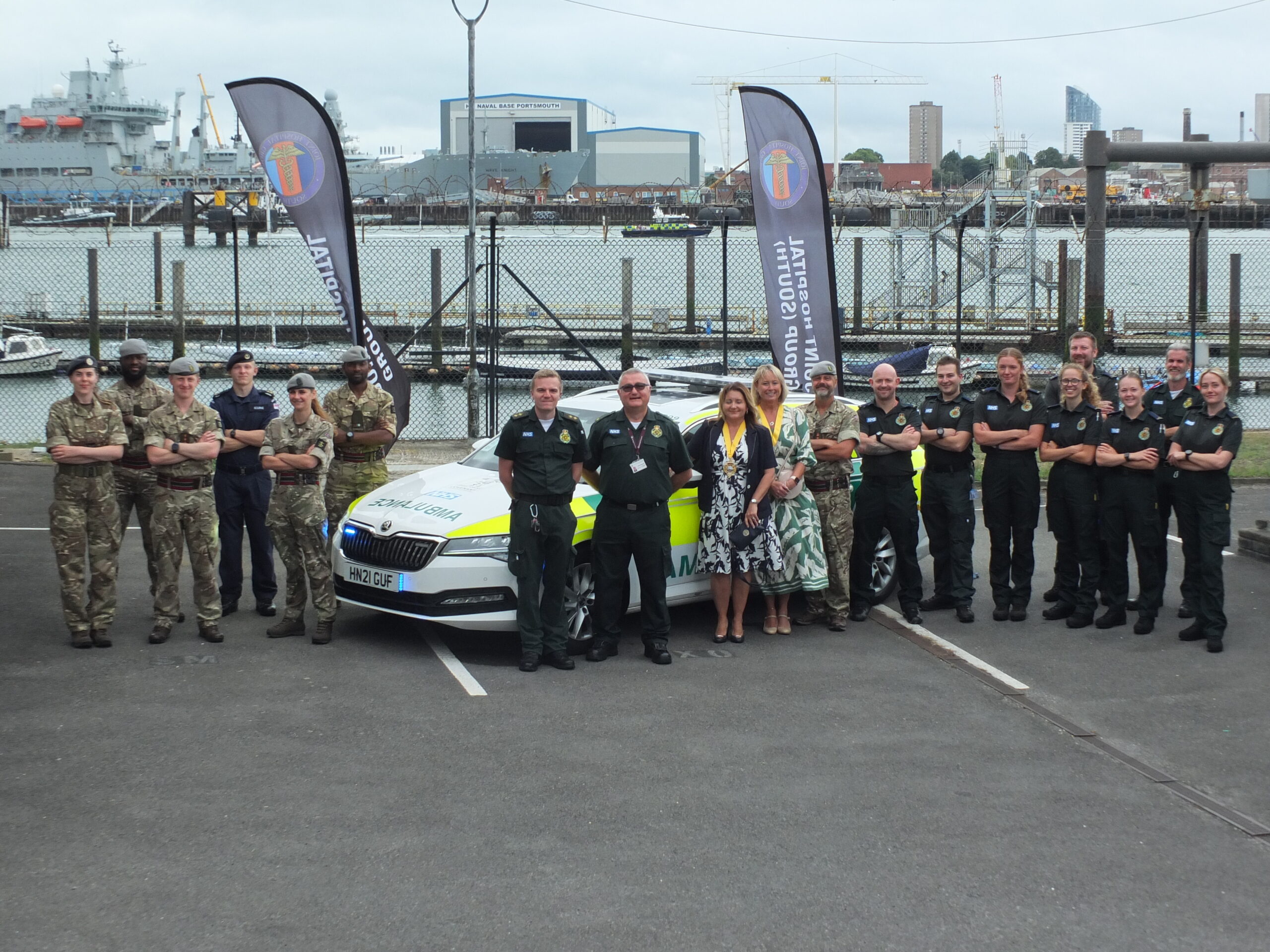 Uniformed military personnel and SCAS staff in front of a ambulance response vehicle