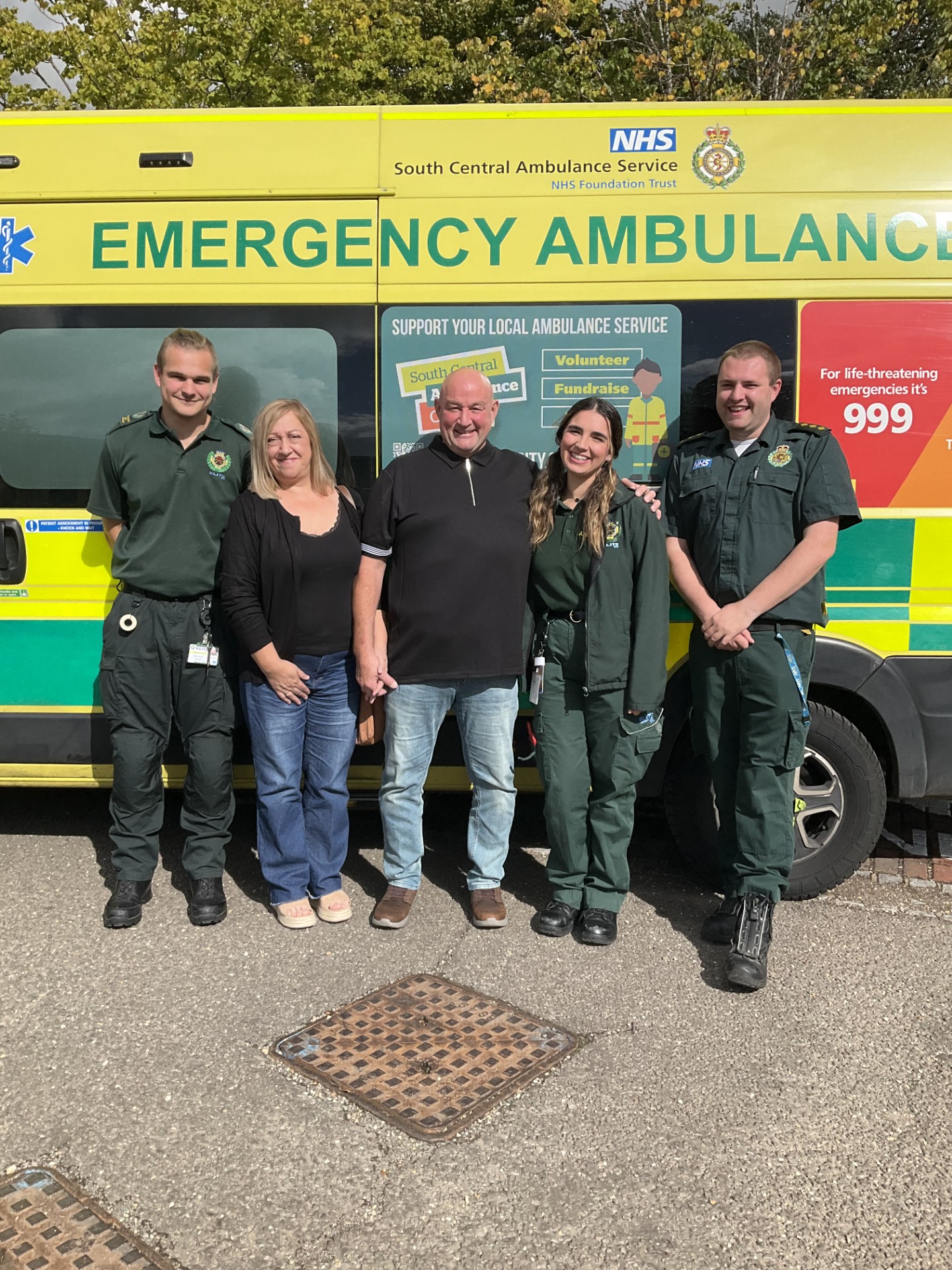 A married couple and three ambulance workers standing in front of an ambulance