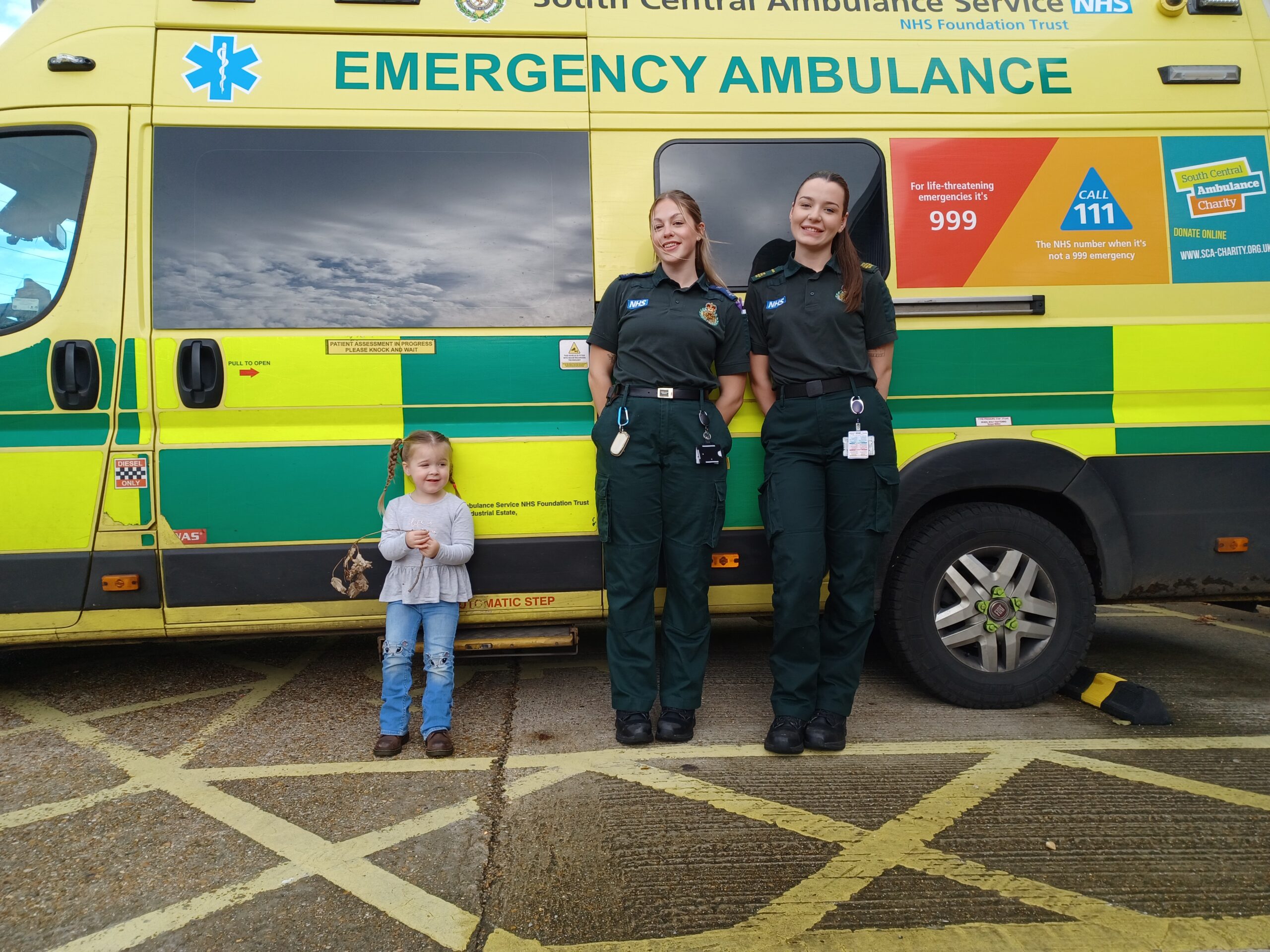 Mabel Summer and Mia A three-year-old girl standing in front on an ambulance with a female ambulance crew