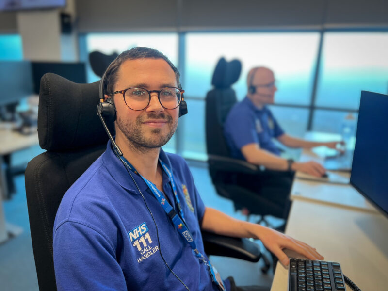 111 calltaker at his desk with a headset on