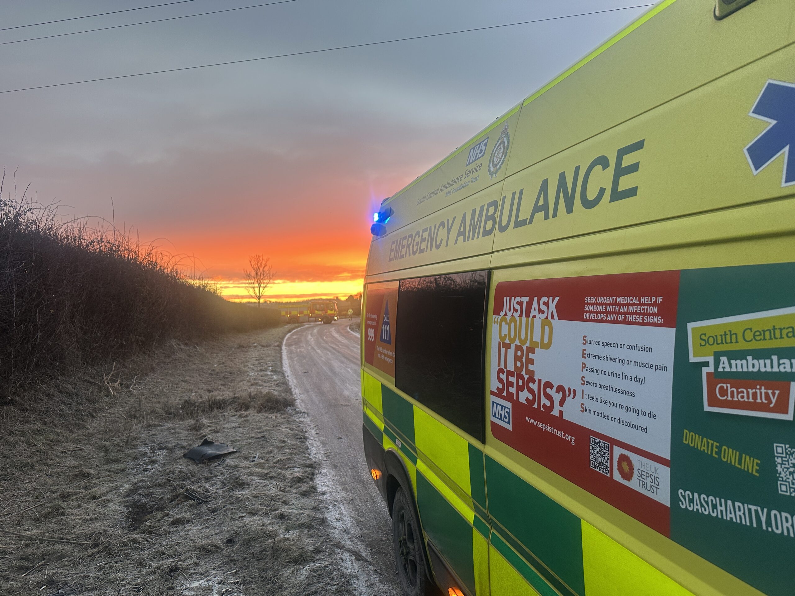 An ambulance parked on an icy country road with a sun rise in the distance