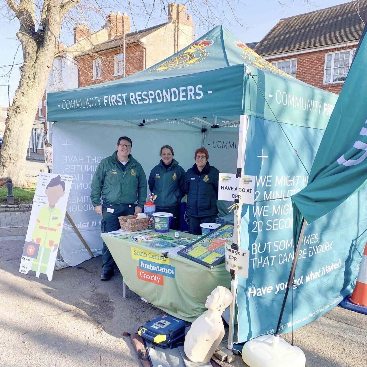 Three volunteer community first responders standing in a small gazebo at the Olney Pancake Race event