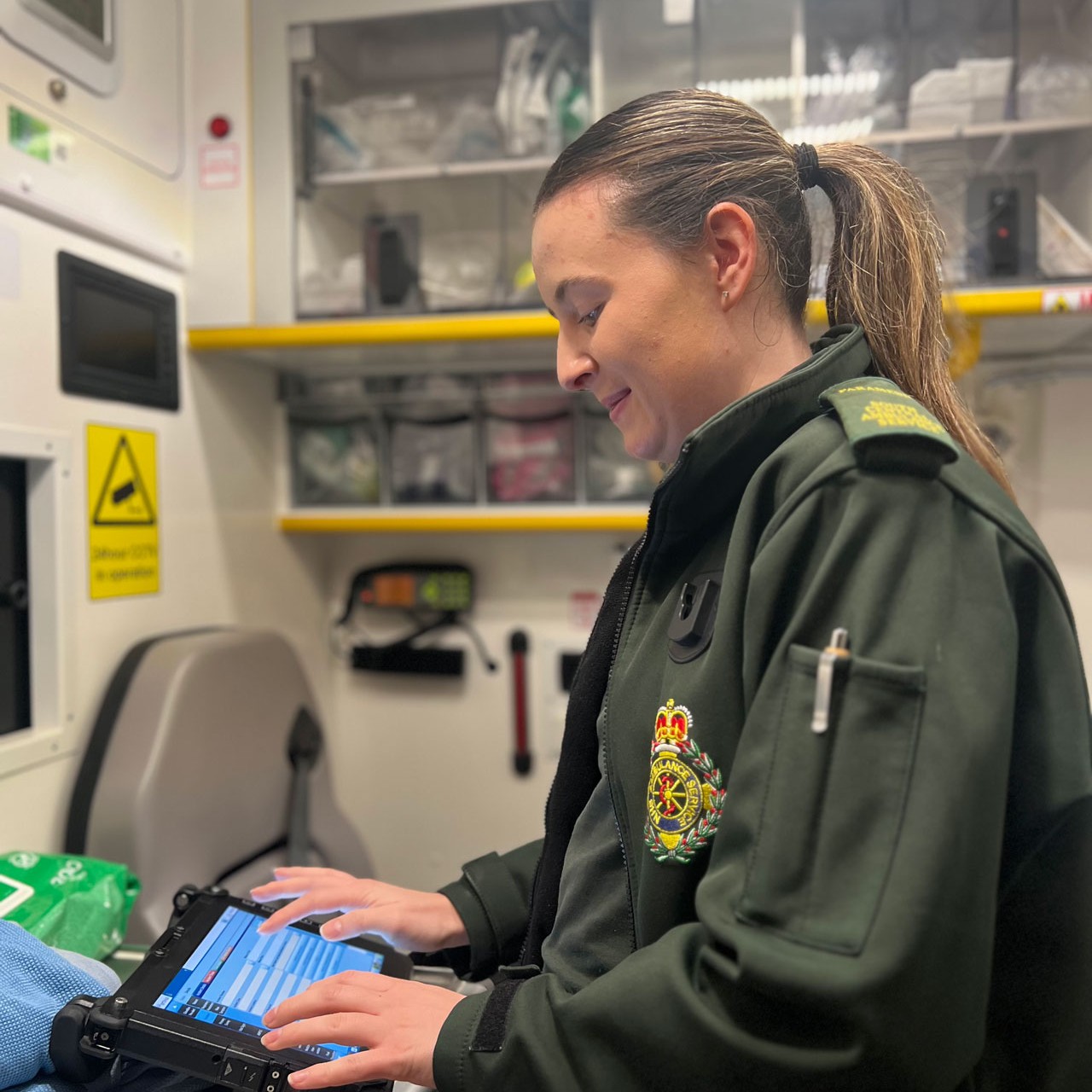 A female paramedic inside an ambulance working on an electronic patient record template
