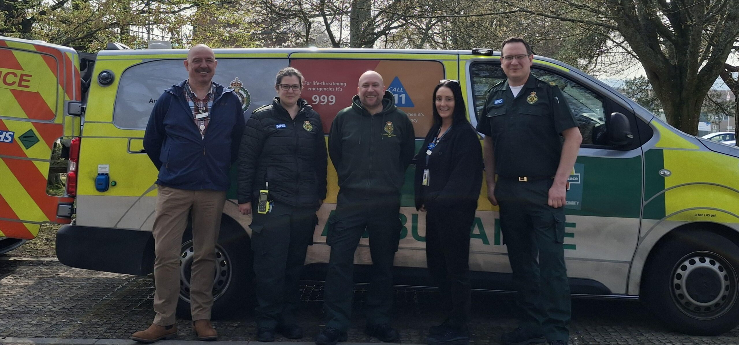 Five ambulance service staff standing in front of a mental health response vehicle