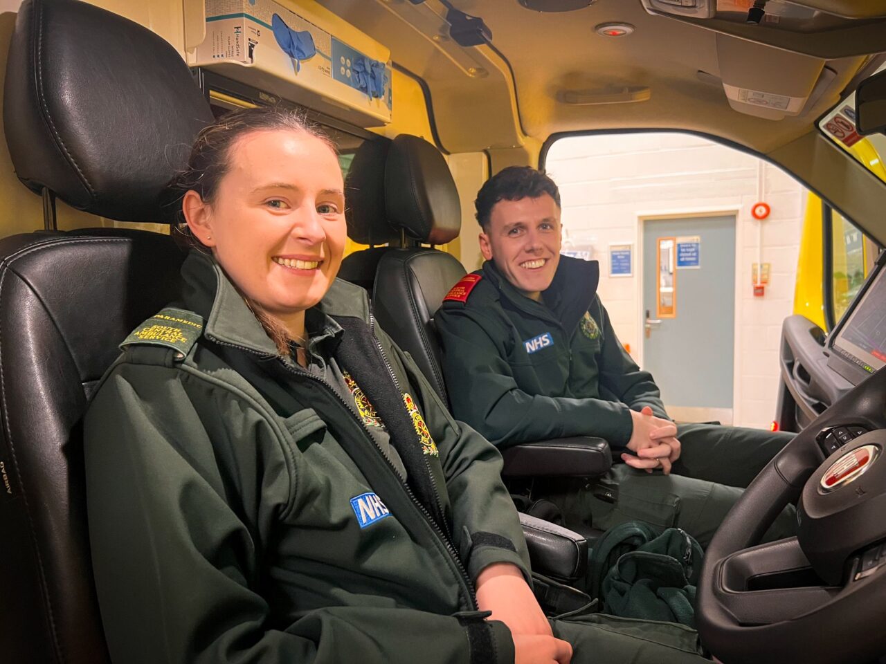 Female and male ambulance crew sitting in ambulance vehicle cab