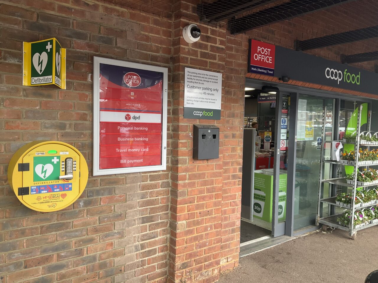 A circular locked yellow cabinet mounted on the wall near the entrance to a Co-op store