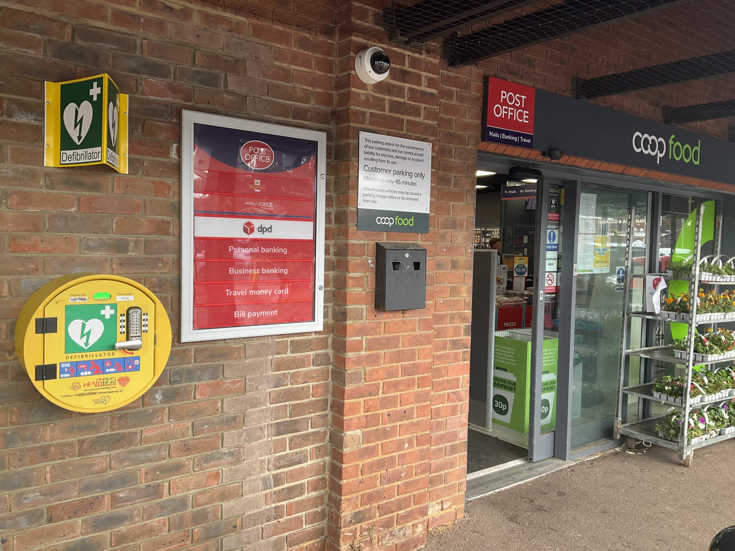 A circular locked yellow cabinet mounted on the wall near the entrance to a Co-op store